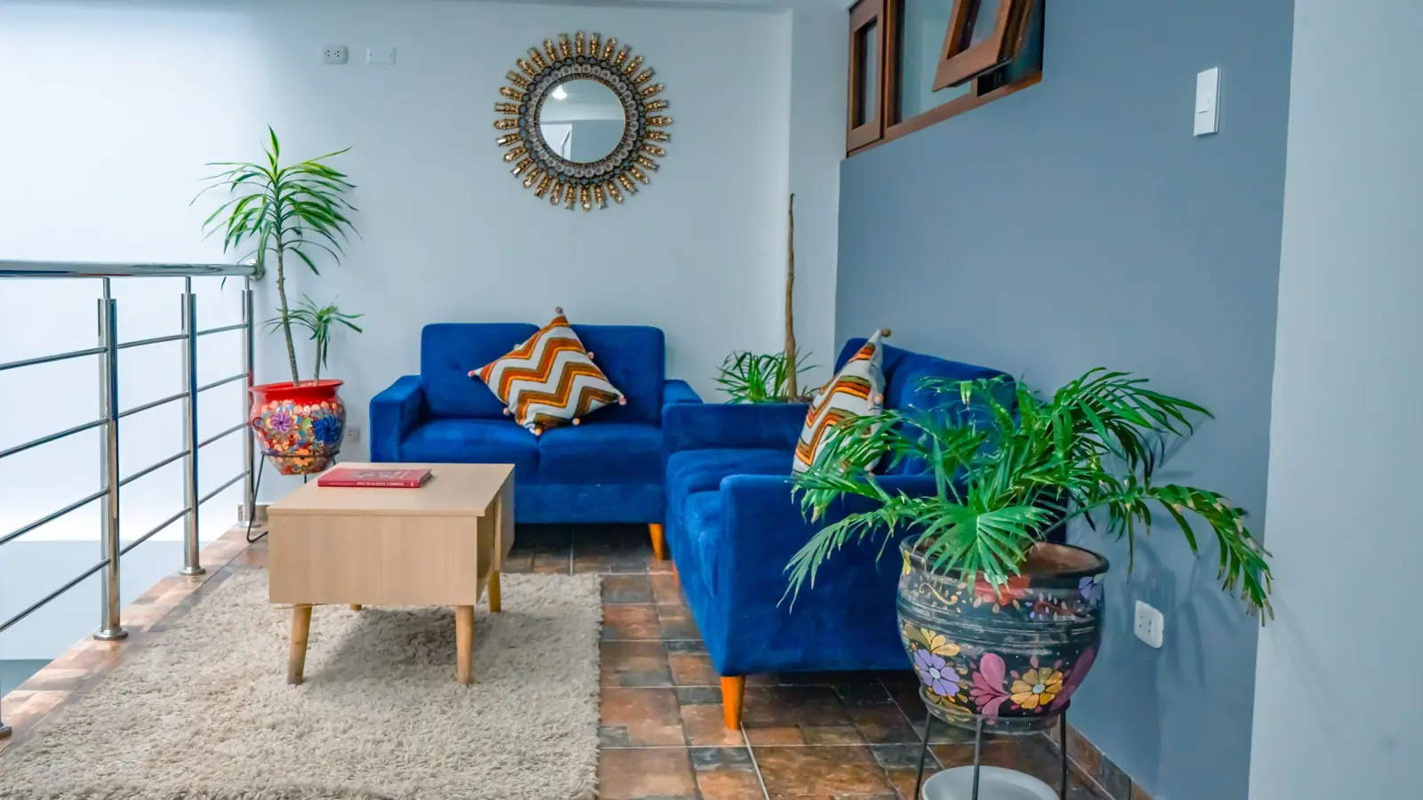 Sala de estar de Ayni con sofás azules, plantas y luz natural