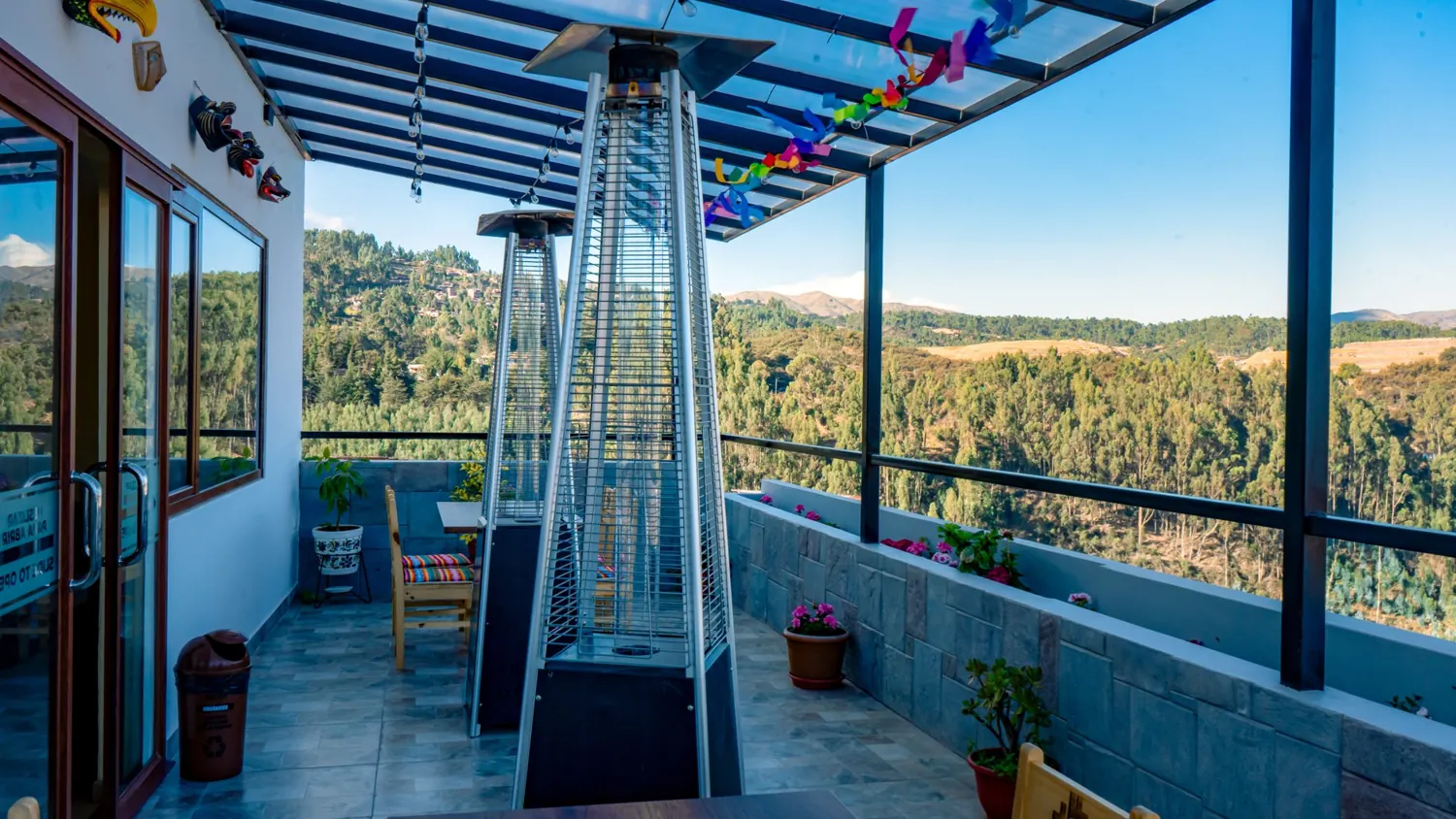 Ayni’s shared viewpoint: covered terrace, tables, plants and the Cusco landscape
