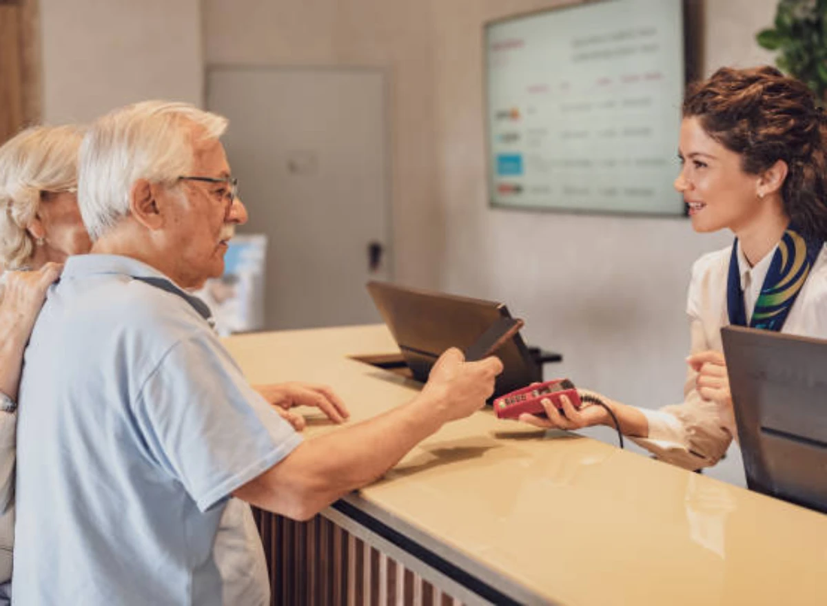 Older adults checking in at the reception of a hotel in Cusco for older adults, with staff assistance, documents, and card payment.
