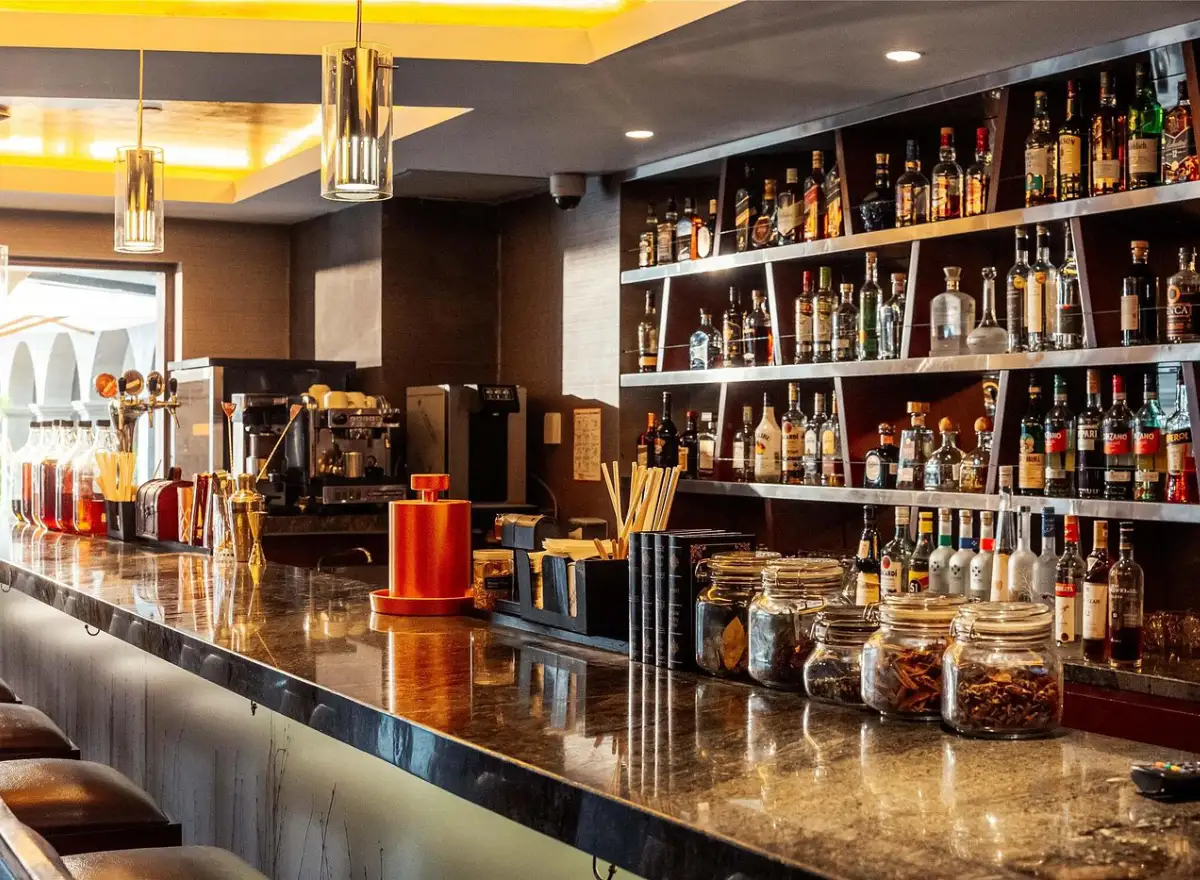 Bar at Hilton Garden Inn Cusco with an illuminated counter, bottles, coffee maker, utensils, and a modern interior.