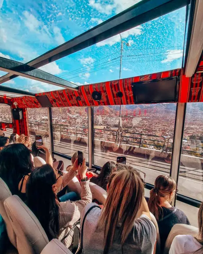 180° panoramic bus city tour in Cusco with comfortable seats and travelers of different ages taking photos of the city.