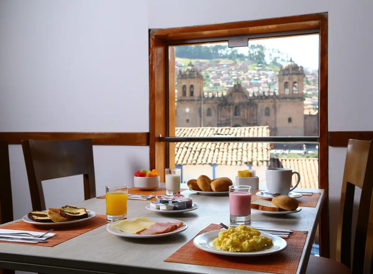 Breakfast at Casa Andina Standard Cusco Plaza with views toward the Cathedral, served dishes, beverages, and a central setting.