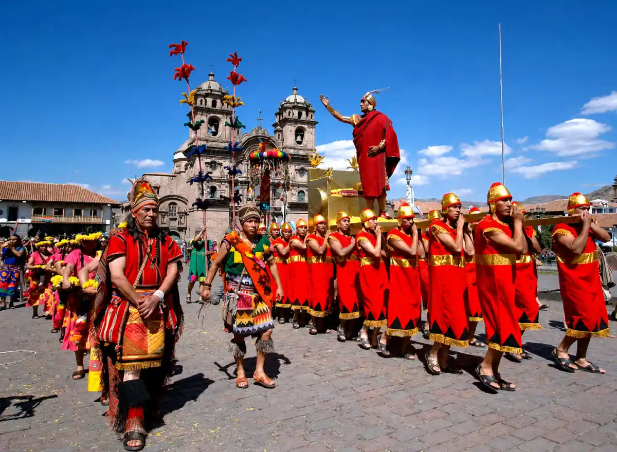 Inti Raymi reenactment in Cusco's Plaza de Armas, with colorful costumes, dancers, and a clear sky.