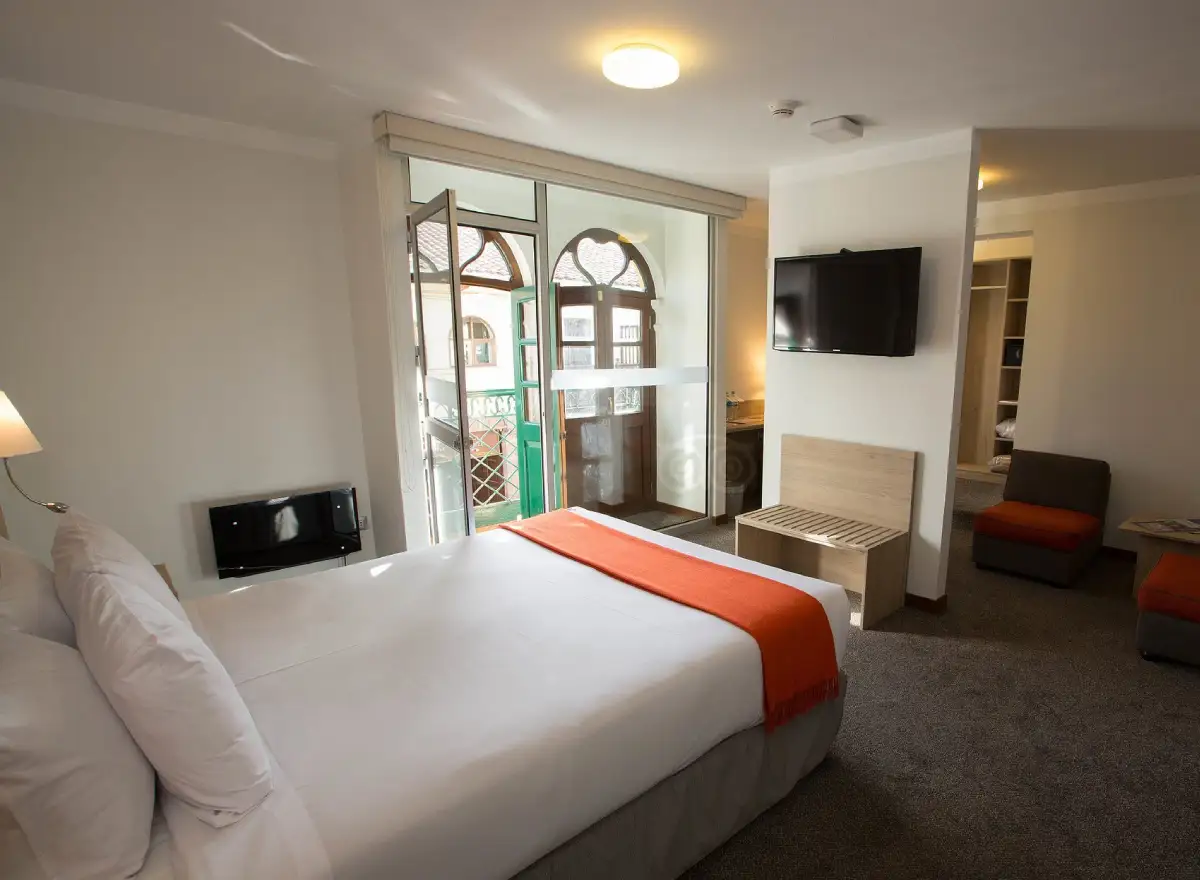 Guest room at Casa Andina Standard Cusco Catedral with a double bed, interior balcony, television, and sitting area.