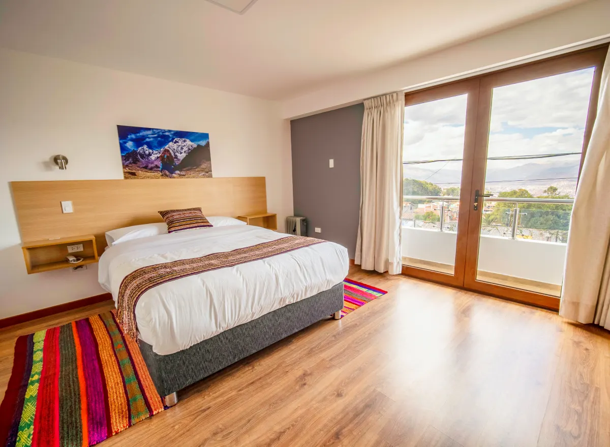 Double-bed room at Ayni Cusco Hotel with a spacious bed, balcony, city view, and Andean-style décor.