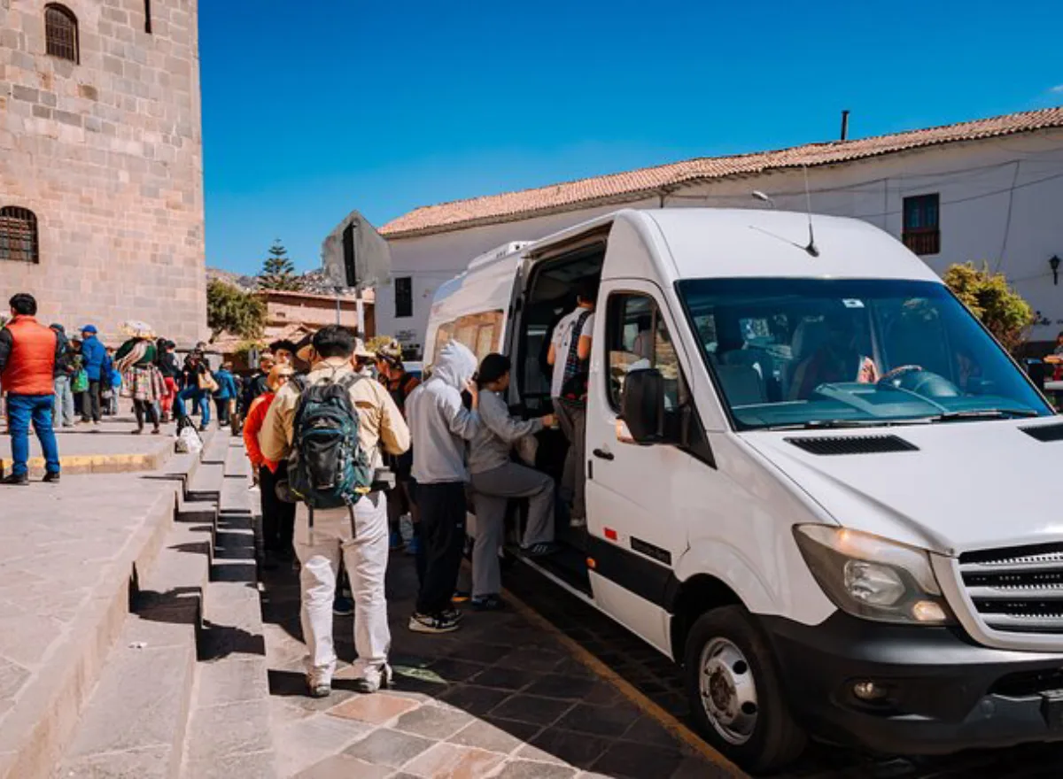 Travelers boarding a tour van outside a hotel in Cusco before starting their scheduled itinerary.
