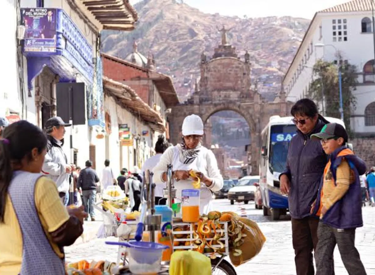 Padre e hijo comprando jugo de naranja artesanal en una calle del Centro Histórico de Cusco, cerca del arco de Santa Clara.